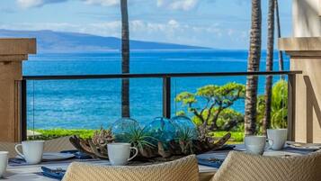 A dining area with a view of the ocean, featuring a table set with white cups and a decorative centerpiece.