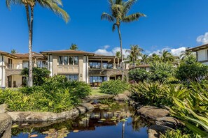 A resort with a pool, palm trees, and a stone bridge.