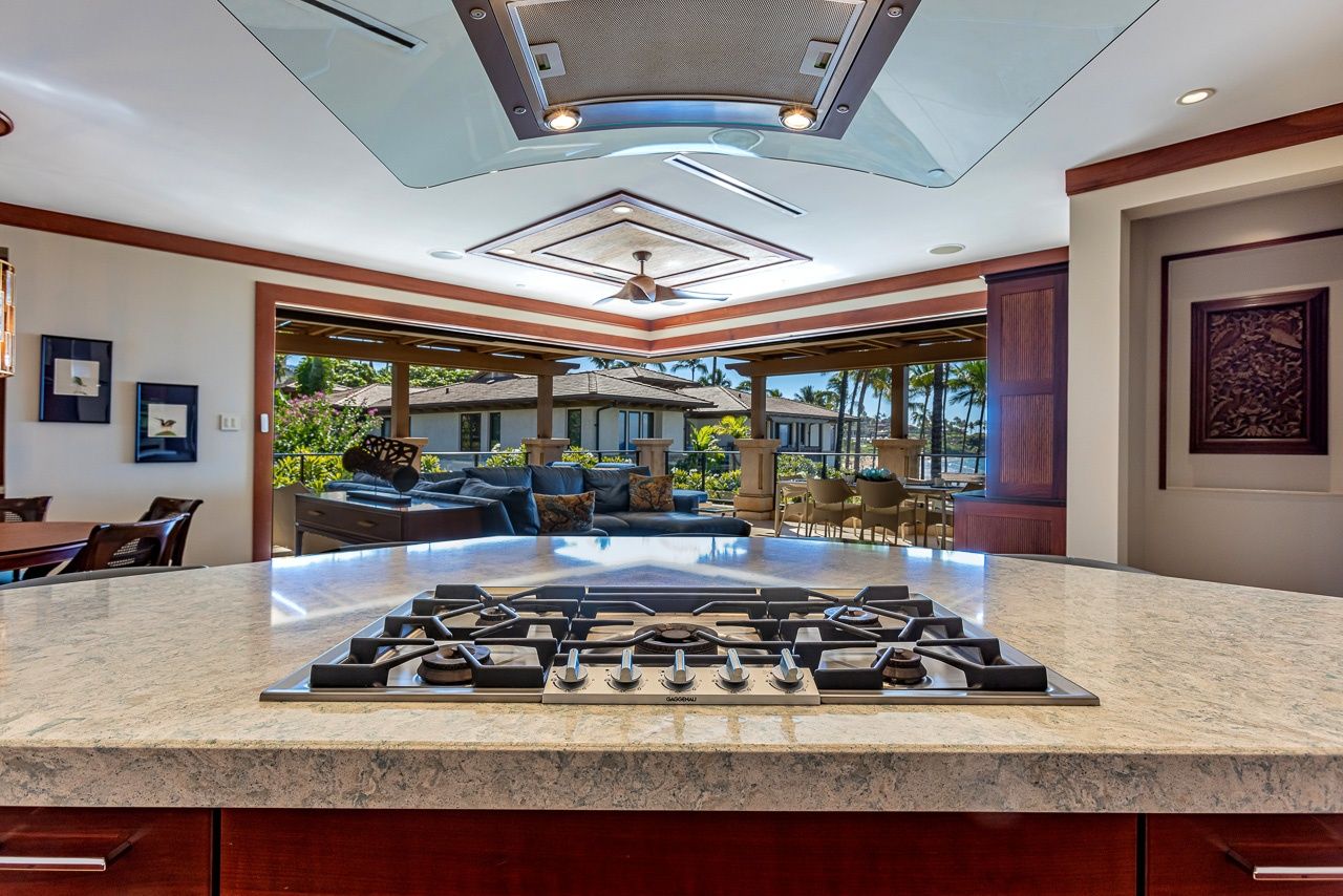 A kitchen with a central island, a ceiling fan, and a view to an outdoor seating area.