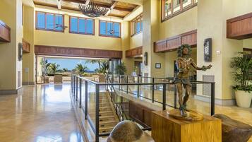 A spacious lobby with a high ceiling, large windows, and a central staircase.