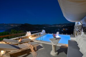 A rooftop pool area with lounge chairs, a small table with candles, and a view of the surrounding landscape. - Fulfill your Holiday Dreams at Mikonos (Mykonos)