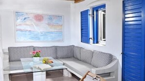 Een moderne woonkamer met een bank, een glazen salontafel en twee houten stoelen.