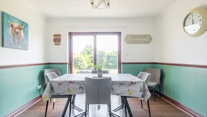 Ein Essbereich mit Tisch für vier Personen, einer Kristallleuchter, einer Uhr und einem Schild mit der Aufschrift 'Seien Sie unser Gast'.