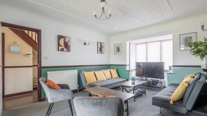Ein modernes Wohnzimmer mit einem grauen Sofa, einem grauen Sessel, einem Holztisch und einem Fernseher.
