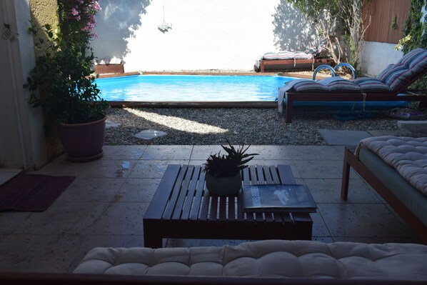 A poolside area with a wooden bench, a potted plant, and a lounge chair. - Maison Caractère Calme, Proche mer (Châteauneuf-les-Martigues)