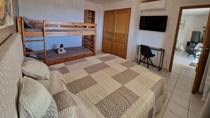 A room with a bunk bed, a desk, a TV, and a wardrobe.