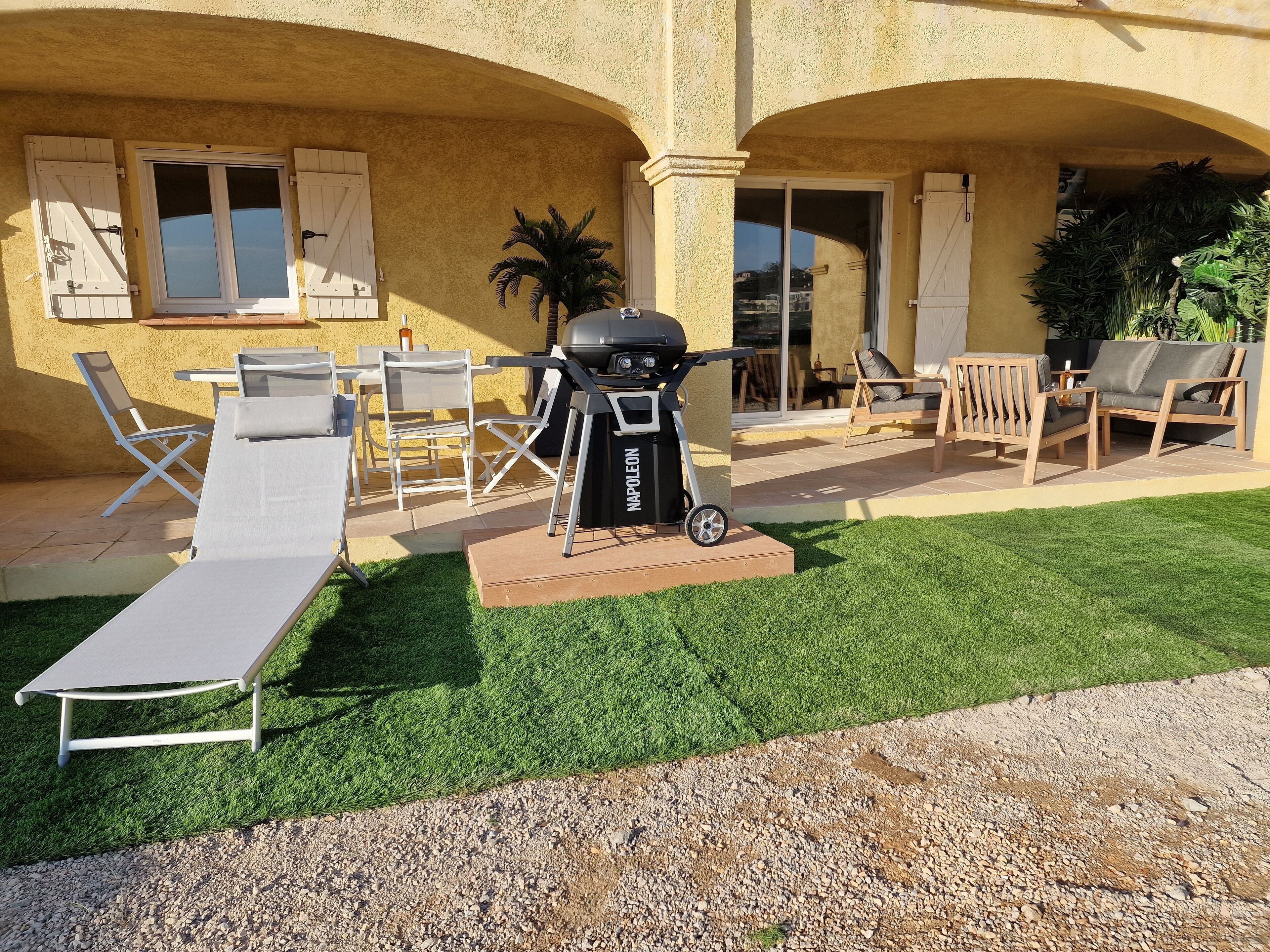 A patio with outdoor furniture, a grill, and a well-maintained lawn.