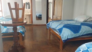 A room with a wooden bed, a round wooden table, and a chair. - Intipunku hospedaje (Cusco)
