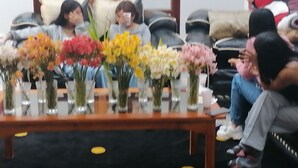 A group of people seated on a couch with vases of flowers in front of them. - Intipunku hospedaje (Cusco)