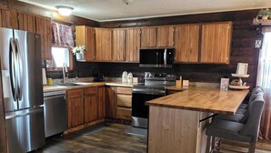 A spacious kitchen with wooden cabinets, stainless steel appliances, and a large island. - Martha's Place (Altura)