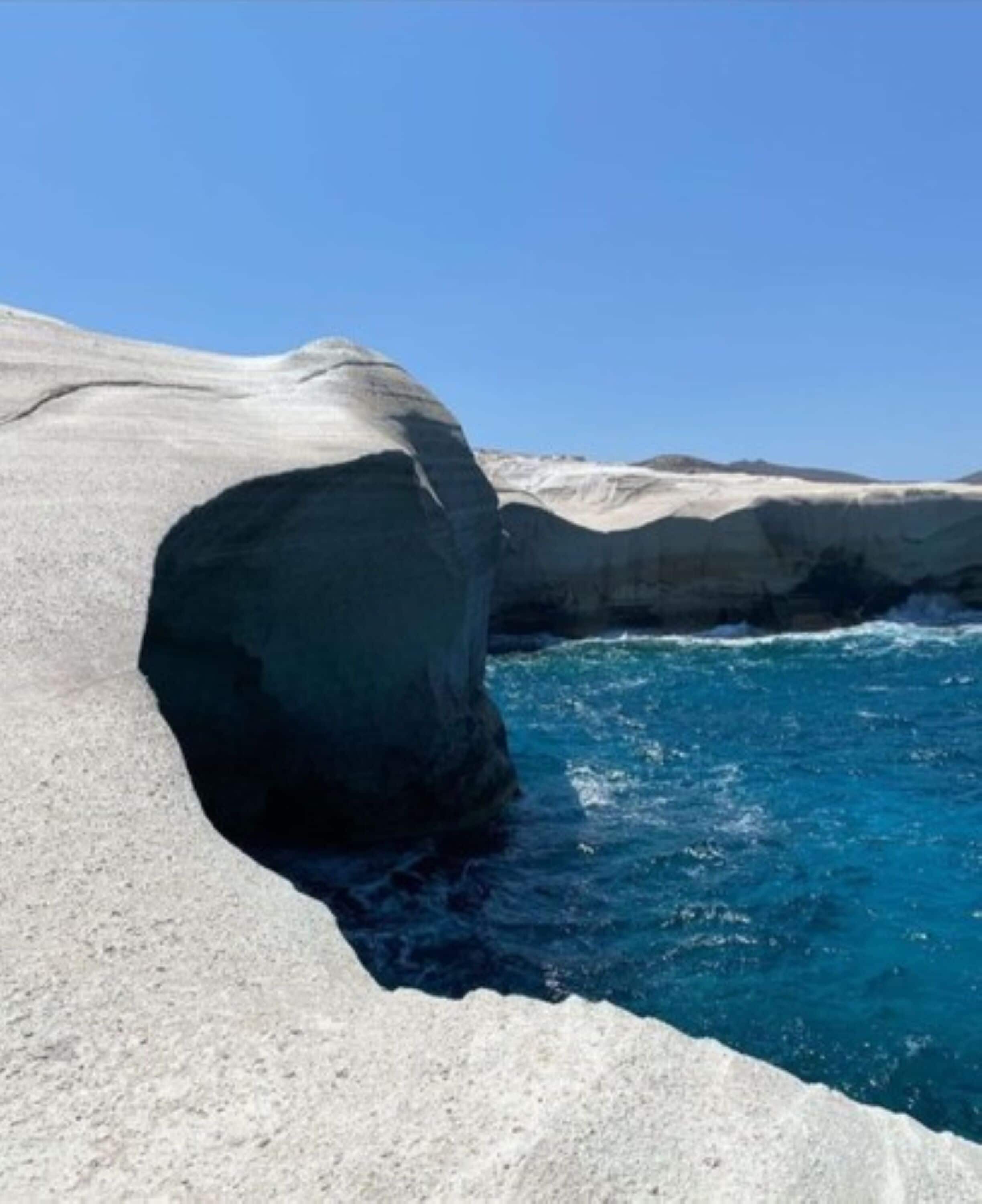 Une grande formation rocheuse, avec une étendue d’eau d’un bleu limpide devant.