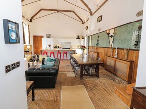 A spacious living area with a large wooden dining table, a black leather sofa, and red bar stools. - Talbot Lodge (Stafford)