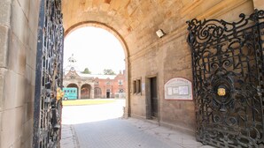 An entrance with a large ornate gate, a brick building, and a clock tower in the background. - Talbot Lodge (Stafford)