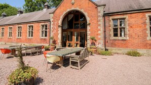A brick building with a large arched entrance, outdoor seating area, and potted plants. - Chetwynd Lodge (Stafford)