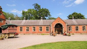 A traditional brick building with a large arched entrance, a carriage, and a gravel courtyard. - Chetwynd Lodge (Stafford)