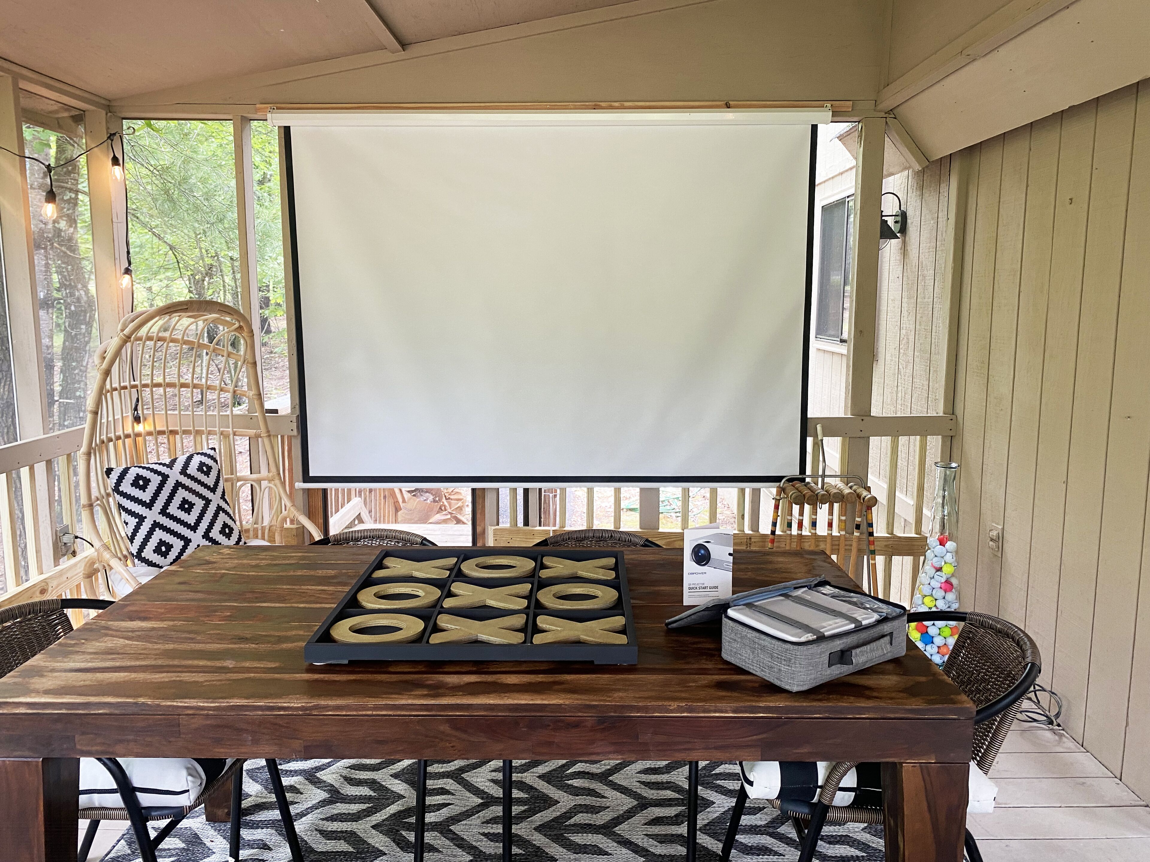 A wooden table with a checkers game set, a projector screen, and a projector.