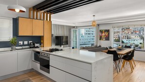 Une cuisine moderne dotée d’un îlot central, d’appareils électroménagers intégrés et d’un coin repas offrant une vue sur la ville.