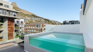 Piscina no terraço com vista desobstruída para uma montanha e edifícios residenciais ao fundo.