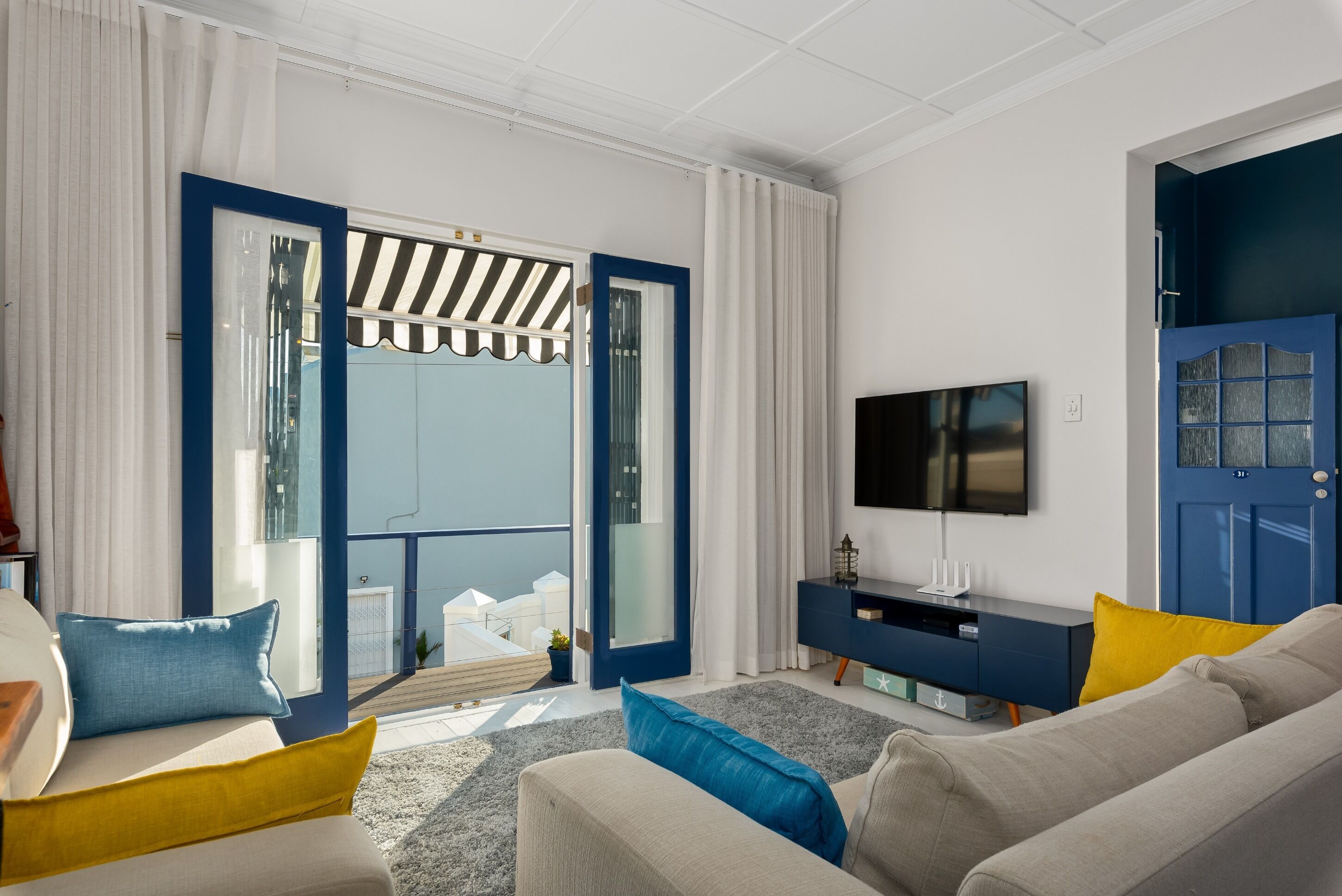 En moderne stue med sofa, tv og en balkon med udsigt.