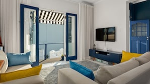 A modern living room with a sofa, a TV, and a balcony with a view. - Grecian Haven In Greenpoint Pool and Braai (Cape Town)