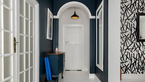 A hallway with a white door, a blue cabinet, and a black and white patterned wall. - Grecian Haven In Greenpoint Pool and Braai (Cape Town)