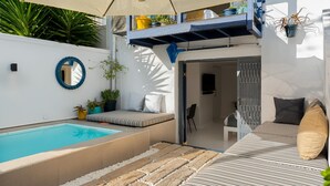 A modern outdoor living area with a pool, seating, and potted plants. - Grecian Haven In Greenpoint Pool and Braai (Cape Town)