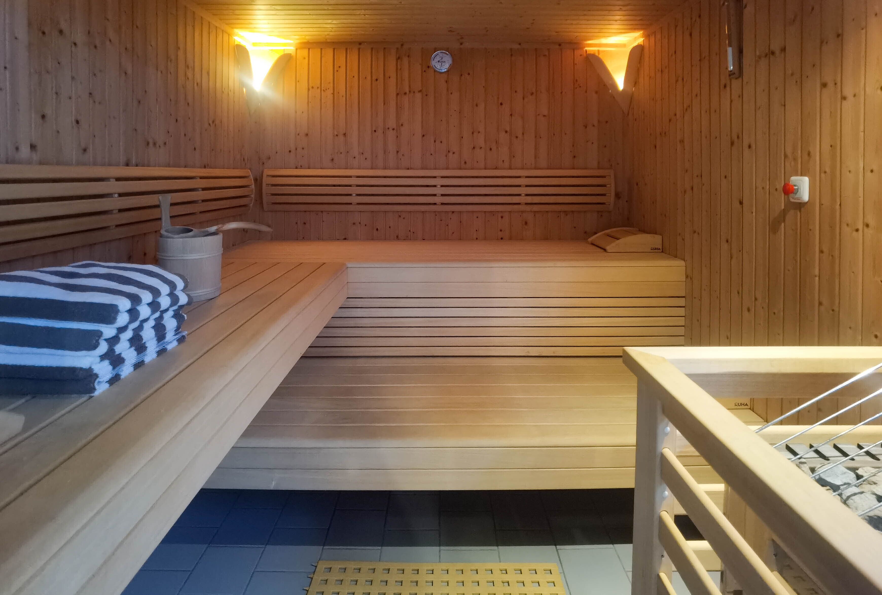 Una sauna amb grans bancs de fusta, un banc amb una tovallola, i un banc amb tovallola i ampolla.