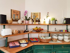 Een ontbijtbuffet met diverse etenswaren, manden en keukengerei op houten planken en aanrechtbladen.