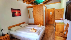 Ein Schlafzimmer mit einem hölzernen Bett, einem Nachttisch, einem Schreibtisch mit Stuhl und einem Spiegel.