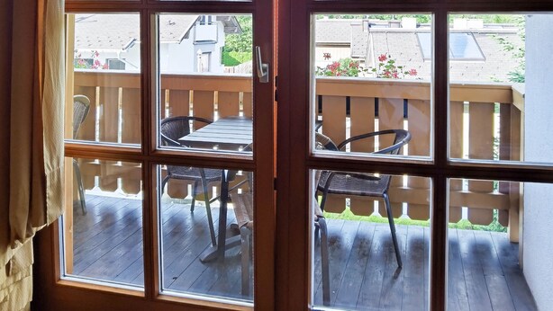 Ein Zimmer mit einem großen Fenster und Blick auf eine Terrasse mit Gartenmöbeln.