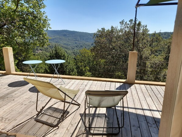 A wooden deck with two round tables and two chairs, overlooking a forested valley. - Pretty house near nature and Verdon and sea (Montferrat)