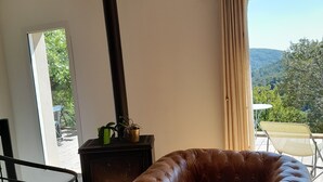 Uma sala de estar acolhedora com poltrona de couro, luminária pendente grande e lareira a lenha.