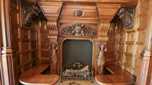A wooden theater with ornate carvings and two wooden benches. - Highcliffe Manor (Bridlington)