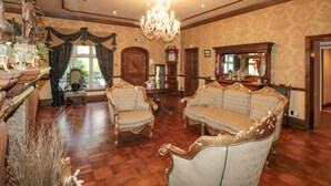 A grand room with ornate furniture, a chandelier, and a large mirror. - Highcliffe Manor (Bridlington)