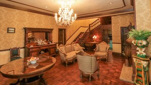 A spacious living room with a chandelier, a staircase, and a dining area with a round table. - Highcliffe Manor (Bridlington)