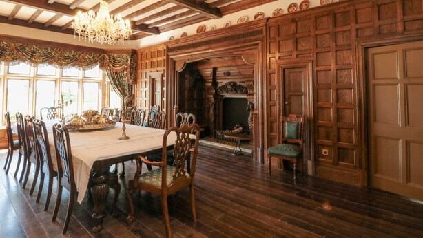A dining room with a long table, wooden chairs, a chandelier, and a fireplace. - Highcliffe Manor (Bridlington)