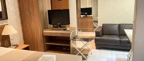 A hotel room with a bed, a desk, a television, a sofa, and a chair.