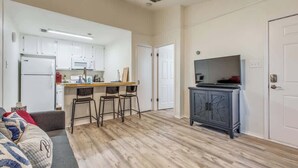 A compact living space with a kitchenette, a dining area with bar stools, a television, and a cabinet. - Cozy Medical Center Retreat in San Antonio (San Antonio)