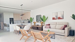 Una sala de estar moderna con un sofá, dos sillones de mimbre, una mesa de centro y un comedor con una mesa y sillas.