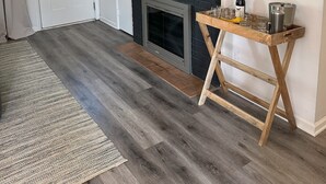 Una sala de estar con chimenea, televisor montado y una mesa de centro de madera.