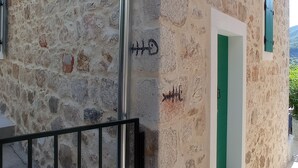 Un bâtiment en pierre avec une porte verte et une rambarde en métal.