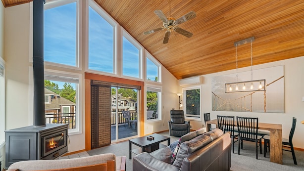A spacious living room with a fireplace, leather sofa, dining table, and chairs. - Stargazer-1/2 blk to the beach and golf course, ocean view from deck MCA#251 (Manzanita)