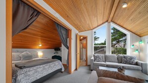 A bedroom with a bed, a sofa, and a large window. - Stargazer-1/2 blk to the beach and golf course, ocean view from deck MCA#251 (Manzanita)