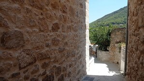 Un étroit sentier de pierre mène à un bâtiment dont la façade est en pierre brute.