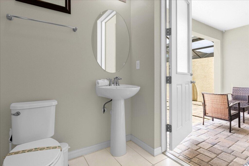 A bathroom with a toilet, sink, and mirror.