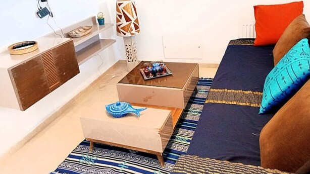 A modern living room with a sofa, coffee table, and a flat-screen TV mounted on the wall. - Au Cœur de Sidi bou Said s+1 (Site archéologique de Carthage)