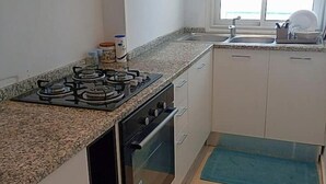 A compact kitchen with a gas stove, oven, and a window providing natural light. - Au Cœur de Sidi bou Said s+1 (Site archéologique de Carthage)