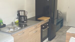 Een moderne keuken met houten kastjes, een zwarte koelkast, een koffiezetapparaat en een spoelbak.