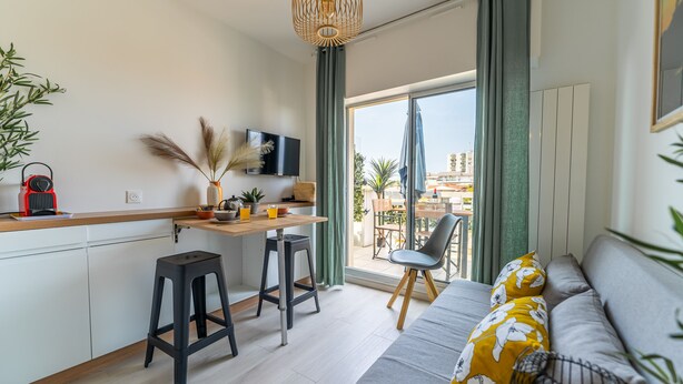 Un appartement moderne doté d’une cuisine, d’un coin repas et d’un balcon offrant une vue sur la ville.
