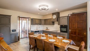 Una cocina moderna con comedor, que incluye una isla grande, electrodomésticos integrados y un reloj en la pared.